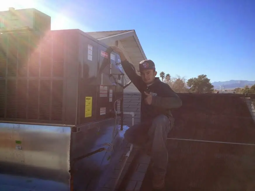 HVAC technician performing Heat Pump Repair on a rooftop unit in Lonsdale